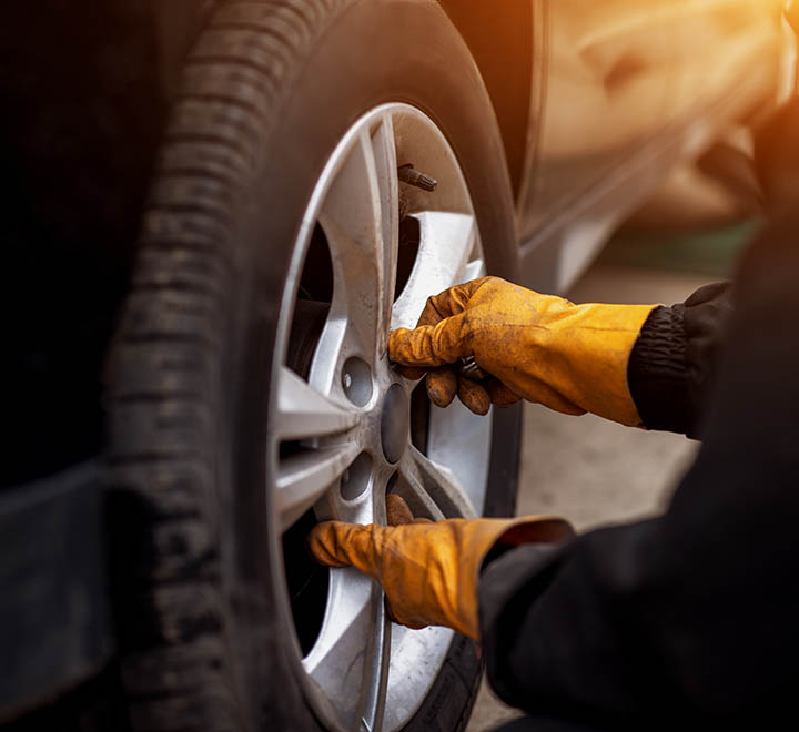 Auto mechanic man with electric screwdriver changing tire outside. Car service. Hands replace tires on wheels. Tire installation concept.