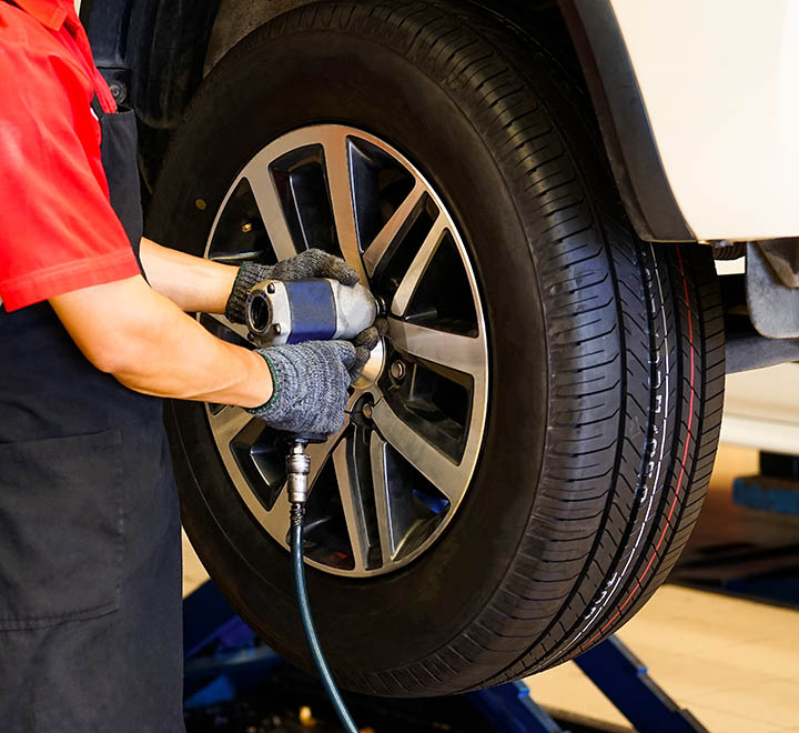 a worker is using a drill to tighten a nut while changing a car tire.selective focus