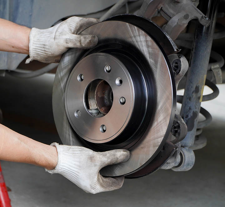 Asian mechanic replaces new brake discs in garage cars.