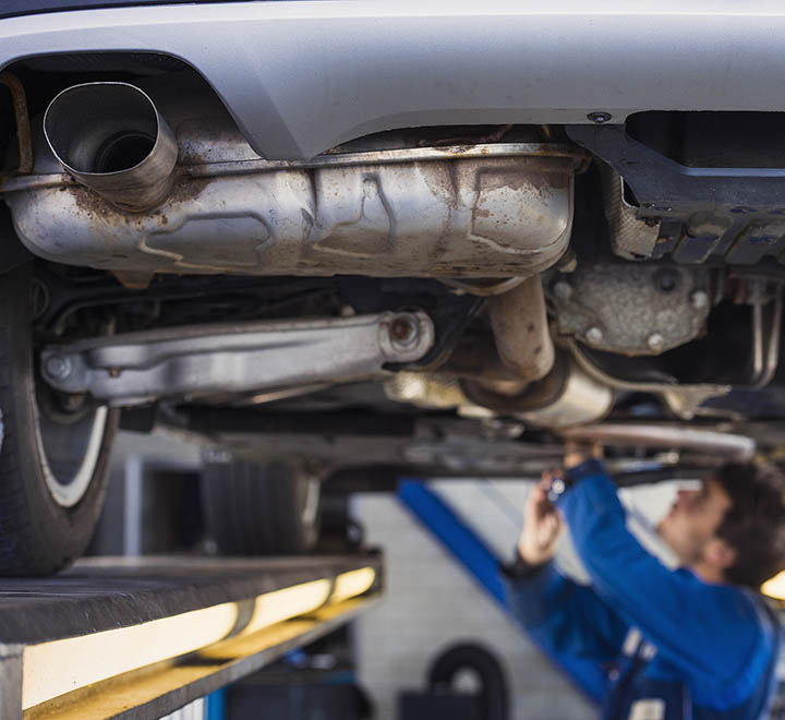 Exhaust of a car on the bridge at a auto repair shop with a mechanic underneath