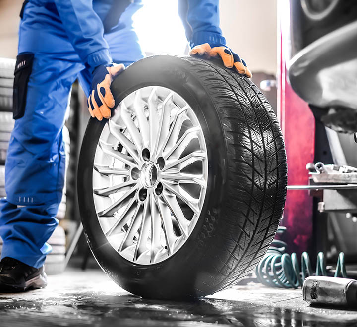 Car mechanic working in garage and changing wheel alloy tire. Repair or maintenance auto service.